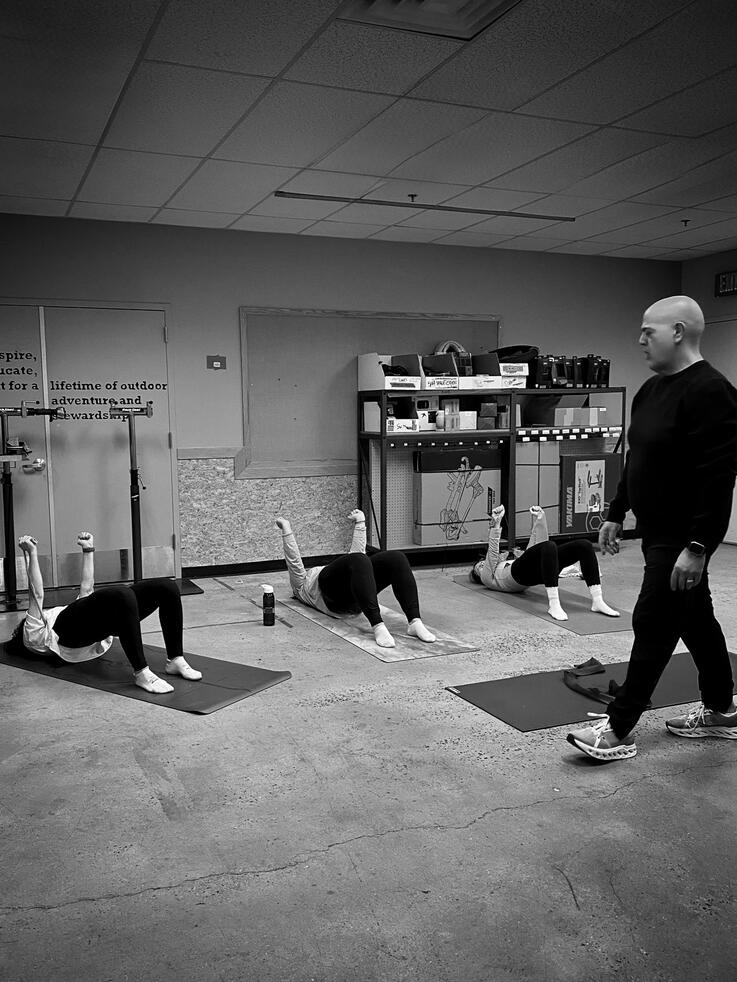 Community Mat Pilates Rafael Jimenez assessing movement and posture during a community Pilates workshop at REI