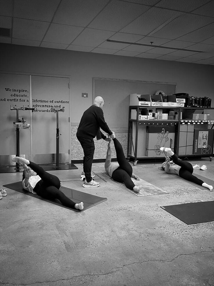 Hands-On Coaching Pilates instructor Rafael Jimenez providing hands-on alignment during a mat Pilates class at REI East Hanover