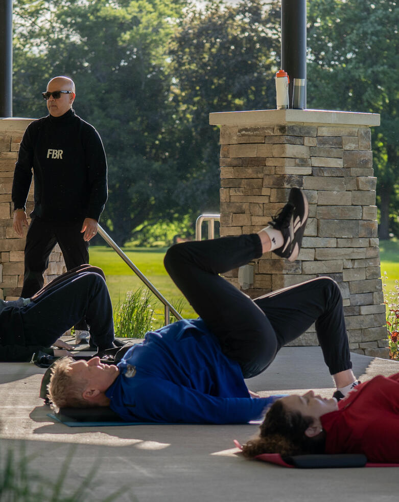 Bridge Work Participants performing a single-leg bridge exercise under instructor observation.