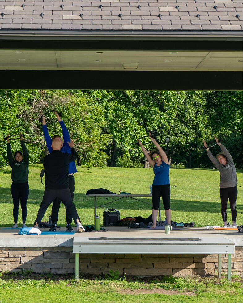 Morning Movement Participants performing standing side stretches beneath the Brookdale Park Gazebo.