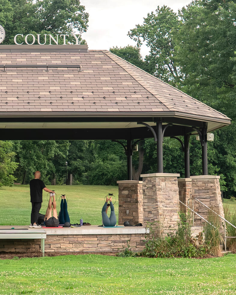 Lower body stretching Participants performing stretches a mat during outdoor Pilates class.